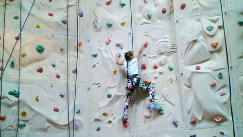 Child climbs on a special wall for mountaineering. the girl of seven years in safety equipment is