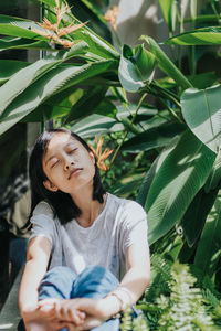 Woman looking away while sitting on plant