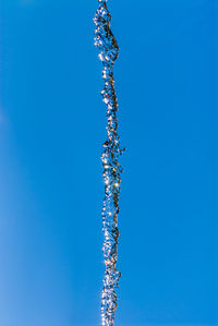 Low angle view of a jet of water against blue sky