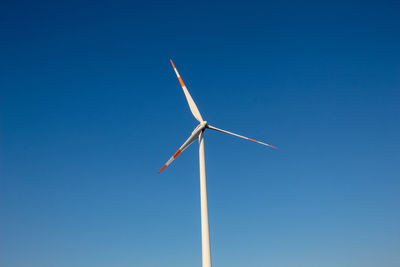 Low angle view of windmill against blue sky