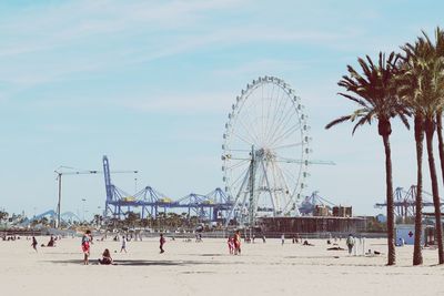 People on beach with ferris wheel in background