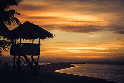 Lifeguard hut on beach against sky during sunset