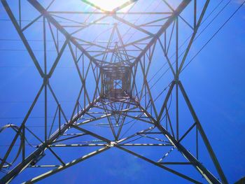 Low angle view of electricity pylon against blue sky