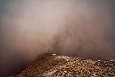 Smoke emitting from mountain against sky
