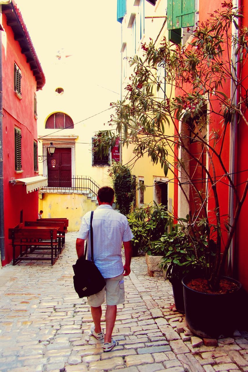 building exterior, rear view, architecture, built structure, lifestyles, full length, street, casual clothing, walking, person, men, leisure activity, city, sidewalk, cobblestone, umbrella, standing, footpath