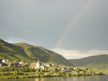 Scenic view of rainbow over mountains and lake against sky