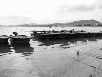 Boats in sea against cloudy sky