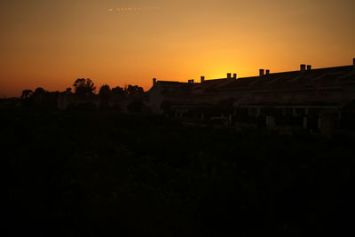 Silhouette buildings against clear sky during sunset