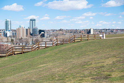 Scenic view of field by buildings against sky