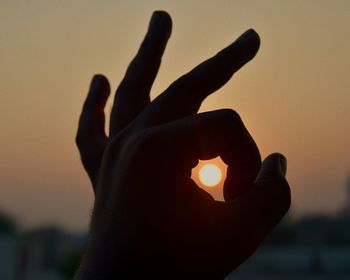 Close-up of silhouette hand against sky during sunset