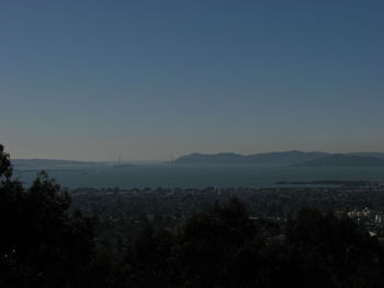 High angle view of cityscape by sea against clear blue sky