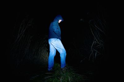 Rear view of man standing on field at night