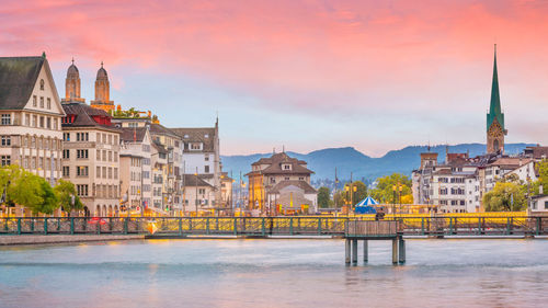 Buildings at waterfront against cloudy sky