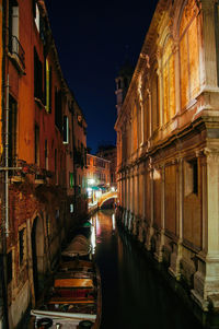 Canal amidst buildings in city at night