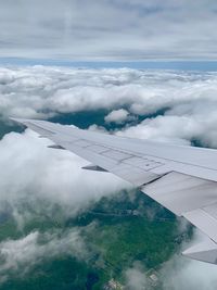 Aerial view of aircraft wing against cloudy sky