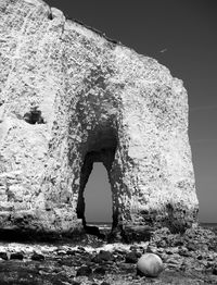 Old stone wall by sea against sky