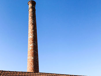 Low angle view of smoke stack against clear blue sky