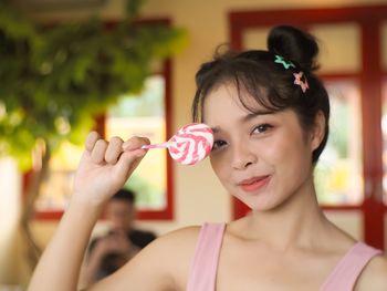 Portrait of smiling young woman holding lollipop