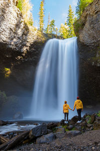 Rear view of woman standing against waterfall