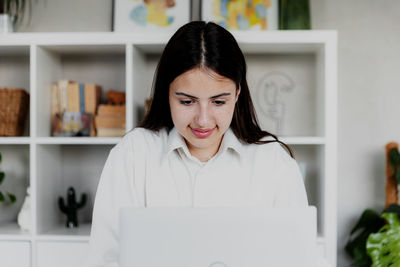 Portrait of young woman using laptop at home