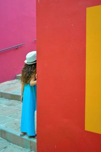 Rear view of girl against red door