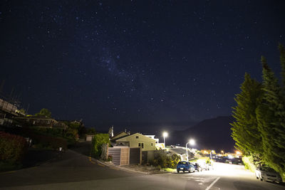 Road amidst buildings against sky at night