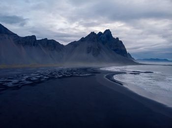 Scenic view of sea and snowcapped mountains against sky