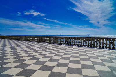 Scenic view of boulevard at sea against blue sky