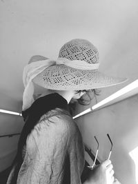 Side view of woman wearing sun hat by wall