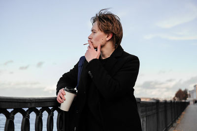 Young man smoking cigarette while standing outdoors