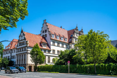 Road by buildings against blue sky