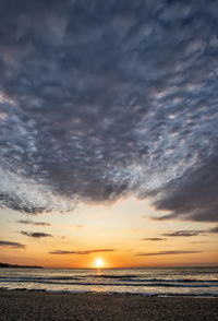 Scenic view of sea against dramatic sky during sunset