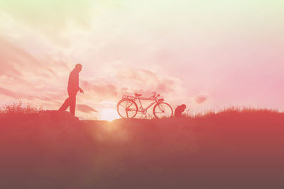 Silhouette people by bicycle on field against sky during sunset