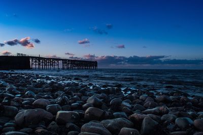 Rocks at sea shore against sky during sunset