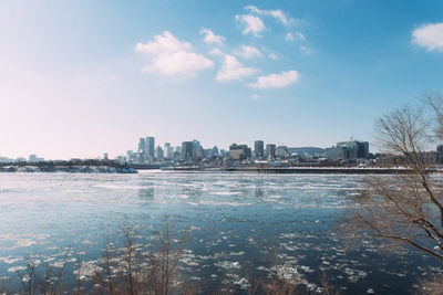 Sea by cityscape against sky