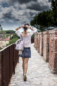 Full length of young woman standing against building