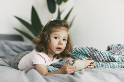 Woman looking away while relaxing on bed at home