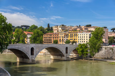 Arch bridge over river in city against sky