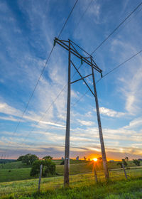 Low angle view of electricity pylon on field against sky