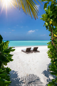 Empty lounge chairs at beach against blue sky