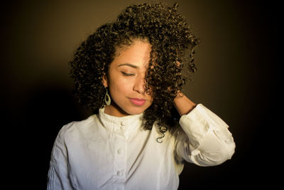 Close-up portrait of young woman against black background