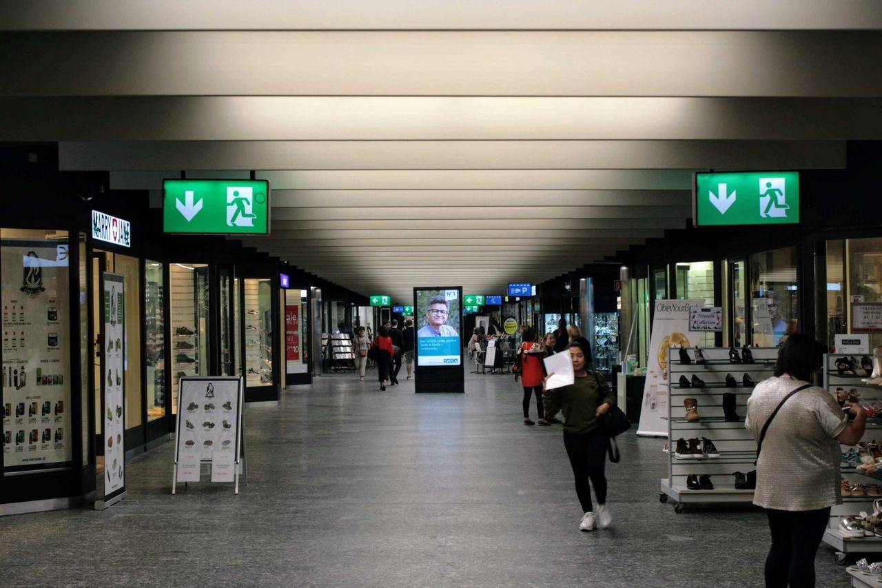 GROUP OF PEOPLE WALKING IN ILLUMINATED UNDERGROUND