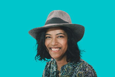 Portrait of young woman wearing hat against blue background