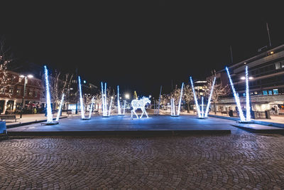 Illuminated light trails on street against sky at night