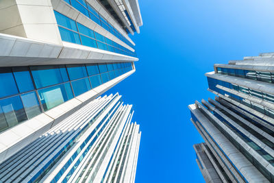 Low angle view of modern buildings against clear blue sky