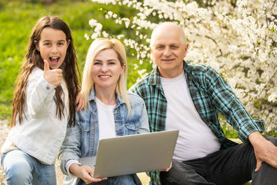 Portrait of young woman with laptop sitting by plant