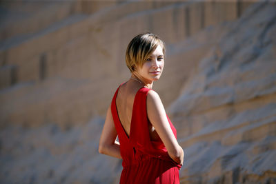 Portrait of young woman standing against rock formations