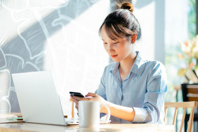 Young woman using laptop while sitting on table