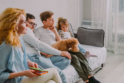 Family sad at home, in a quarrel on the couch, dad, mom, teenage son, preschool daughter, poodle dog