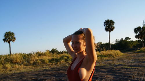 Young woman standing on field against clear sky